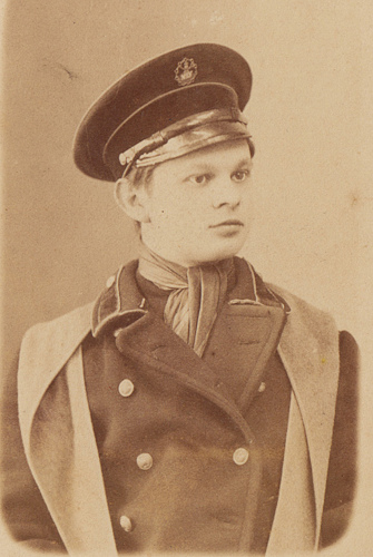 Ученик Уфимского землемерного училища в 
	фуражке и пальто с накинутым башлыком